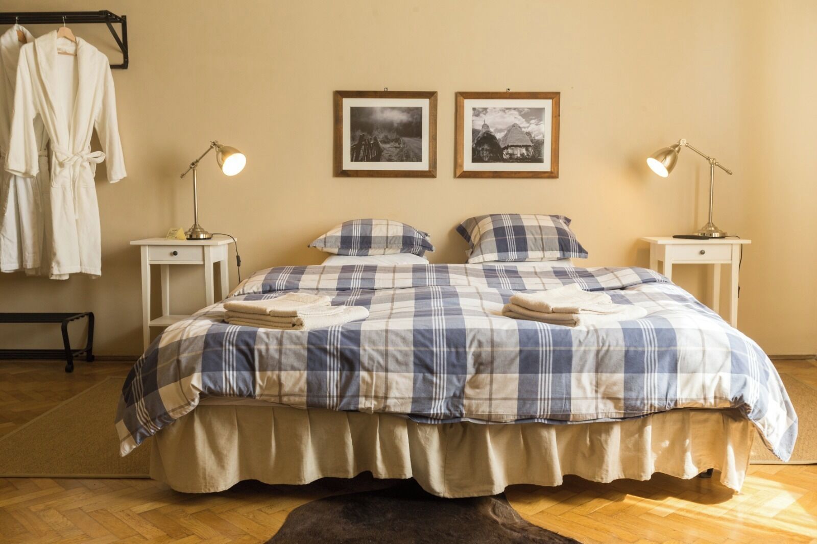 Un dormitorio con una cama grande, dos mesitas de noche, un banco y un armario.