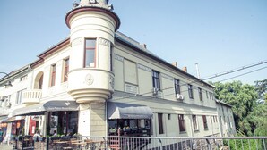 A historic building with a corner turret, multiple windows, and outdoor seating areas. - Ratiu House (Turda)