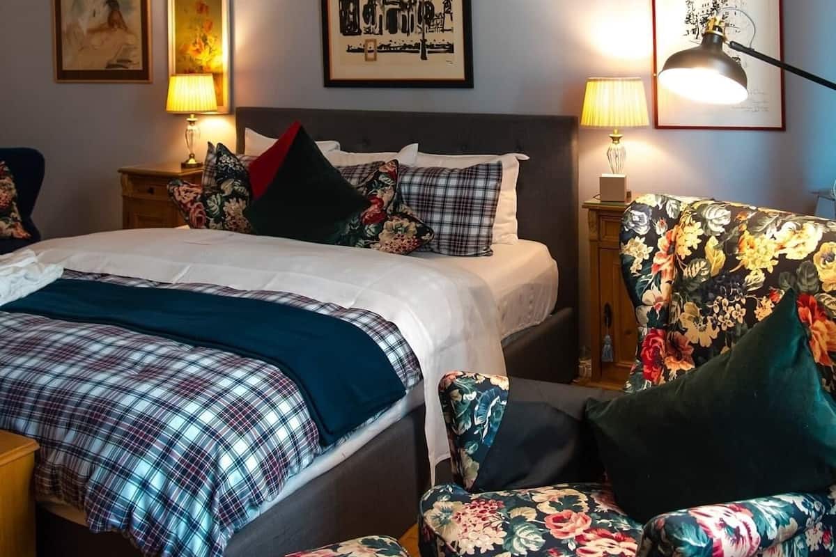 A neatly arranged bedroom with a bed, two side tables, a chair, and wall art.