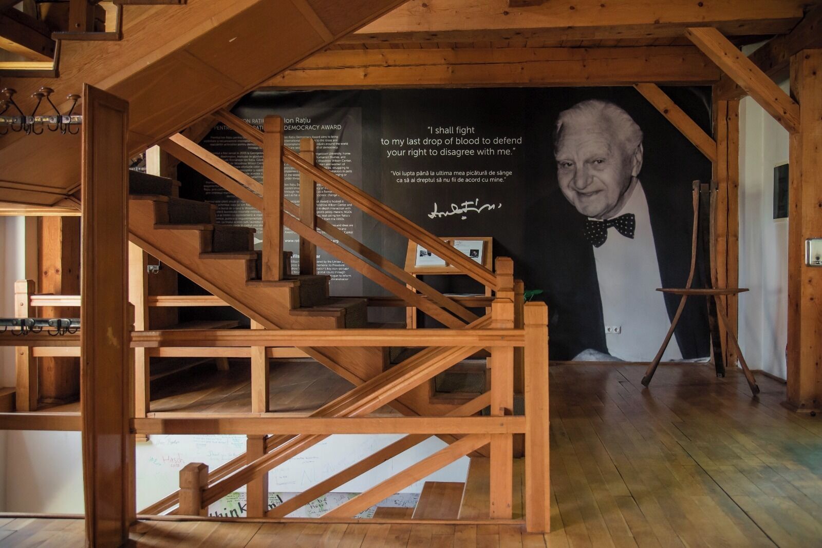 Una escalera de madera con un cartel blanco y negro que muestra una cita y un rostro desenfocado.