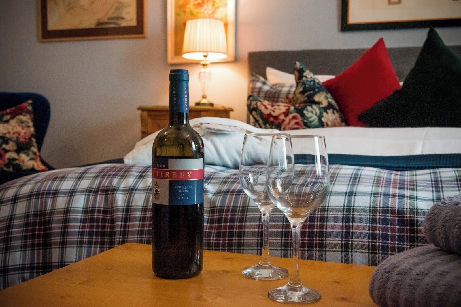 A bottle of wine and two glasses on a table in a hotel room.
