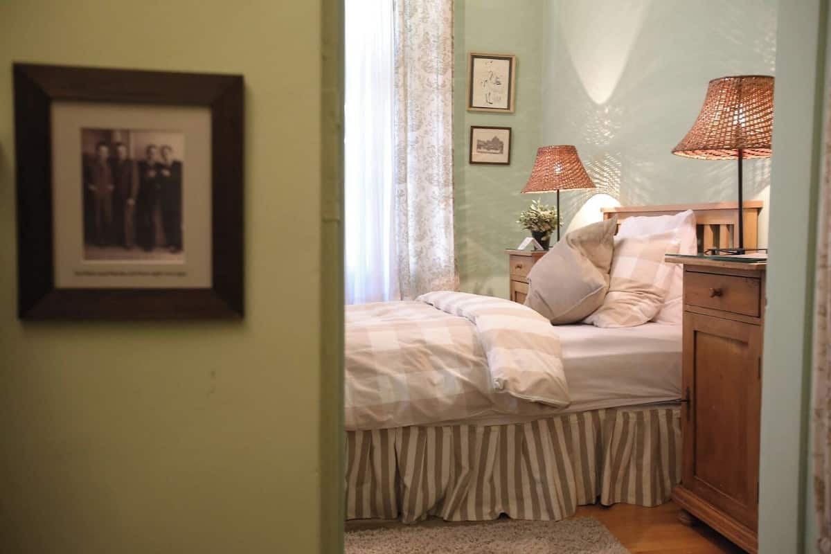 A bedroom with a bed, bedside lamps, a dresser, and a framed picture on the wall.
