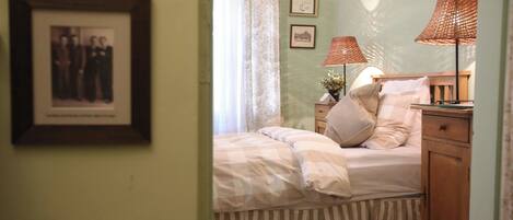 Un dormitorio con cama, lámparas de noche, cómoda y un cuadro en la pared.