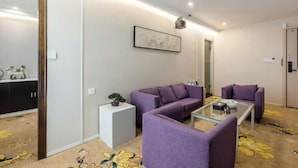 A modern living room with a purple sofa set, a glass coffee table, and a cityscape artwork on the wall. - Cornwall Hotel Chaozhou (Chaozhou)