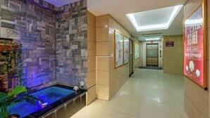 A hotel corridor with a stone wall, a glass elevator, and a sign with Chinese characters. - Cornwall Hotel Chaozhou (Chaozhou)