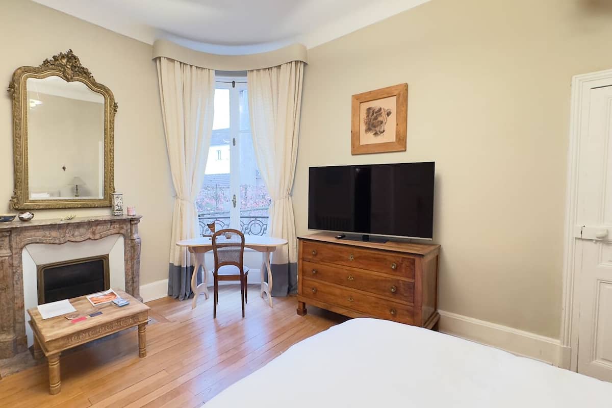 Un dormitorio con chimenea, televisión, escritorio y cama.