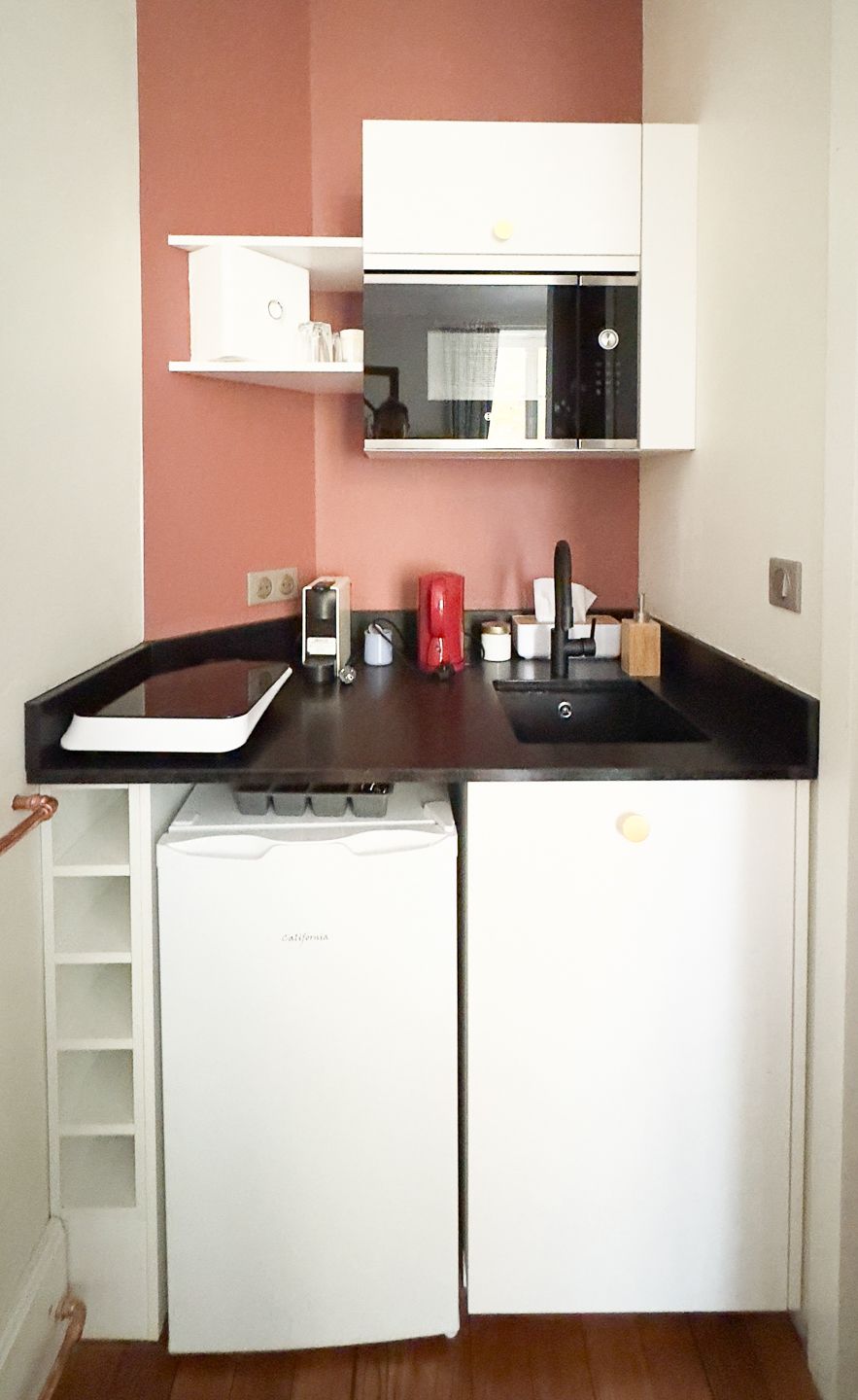 A compact kitchen with a white dishwasher, a microwave, and a sink.