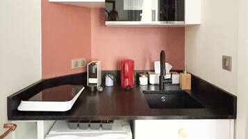 A compact kitchen with a white dishwasher, a microwave, and a sink.