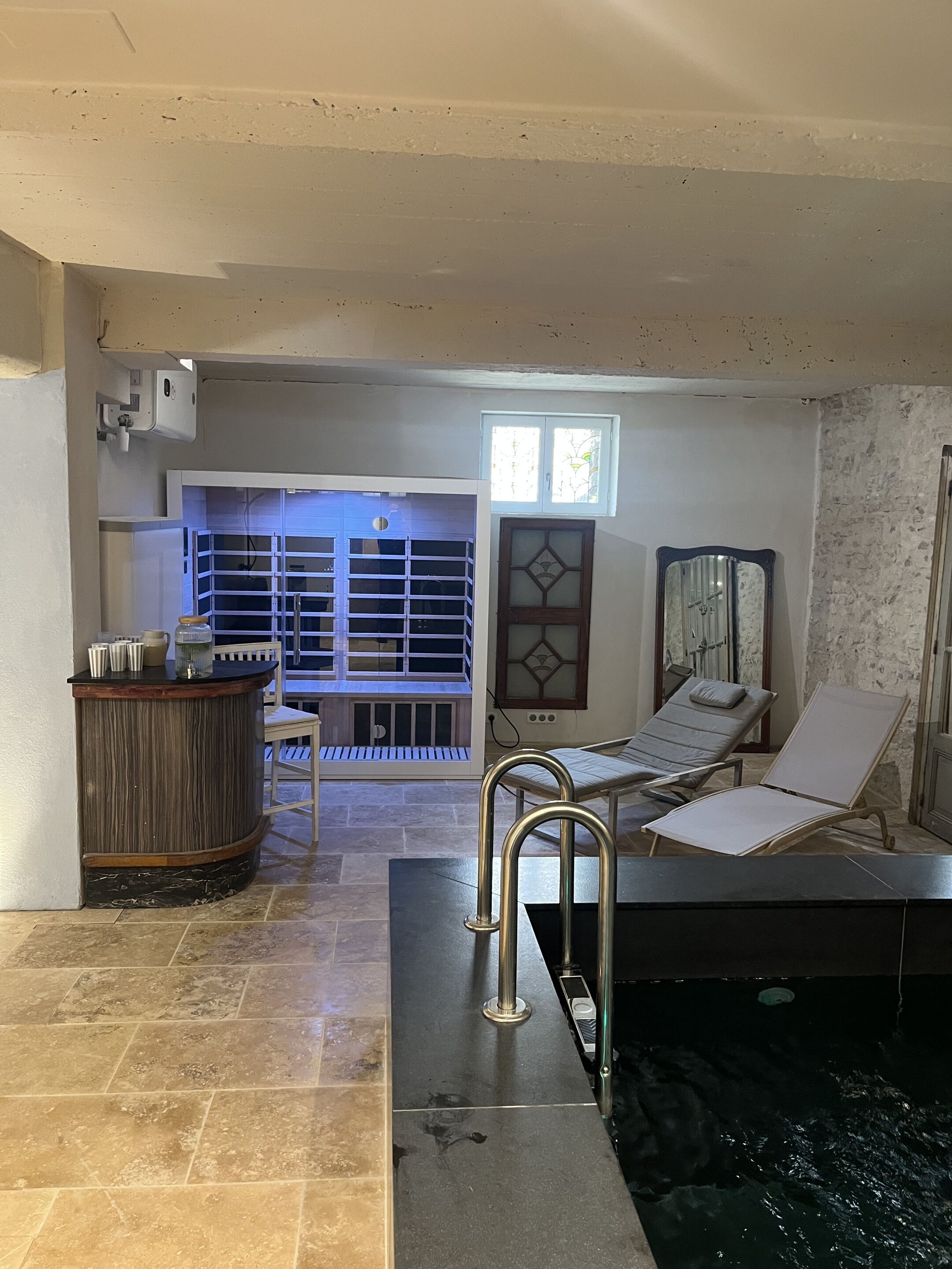 Zona de spa con piscina, mostrador de recepción y área de descanso con vistas a la piscina.