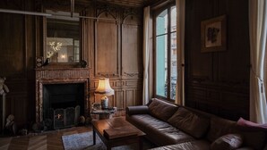 A traditional room with a fireplace, leather sofa, and a table with a lamp. - Suite de l'Opéra  (Vichy)