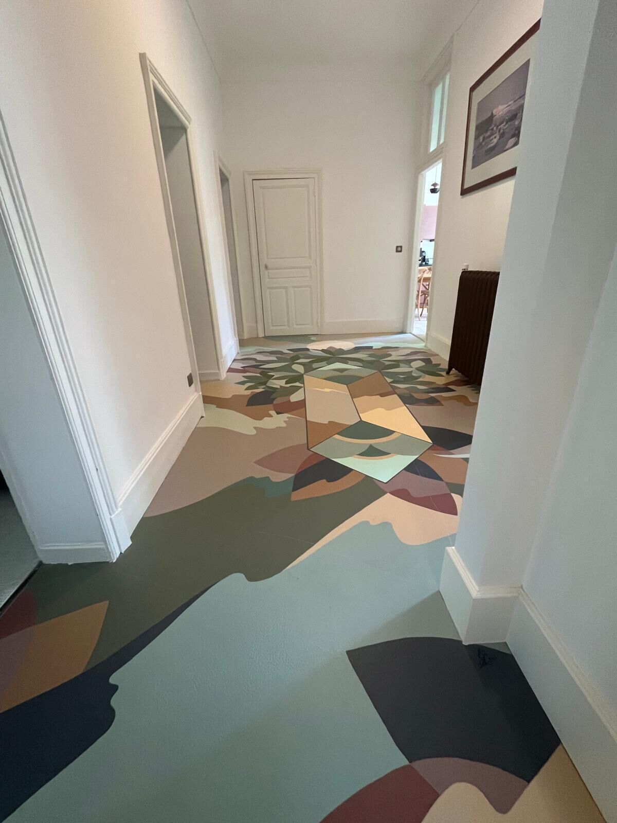 A hallway with patterned carpet, white walls, and a door at the end.