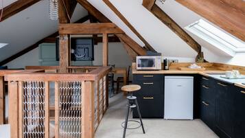 Een compacte keuken met een magnetron, Bosch vaatwasser en houten meubels.