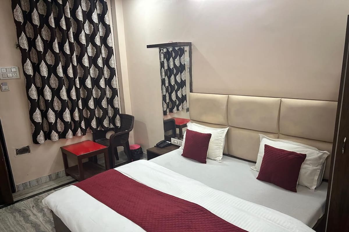 A hotel room with a large bed, a desk, a chair, and a mirror.