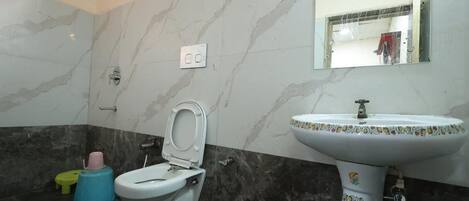 A bathroom with a toilet, sink, and mirror.