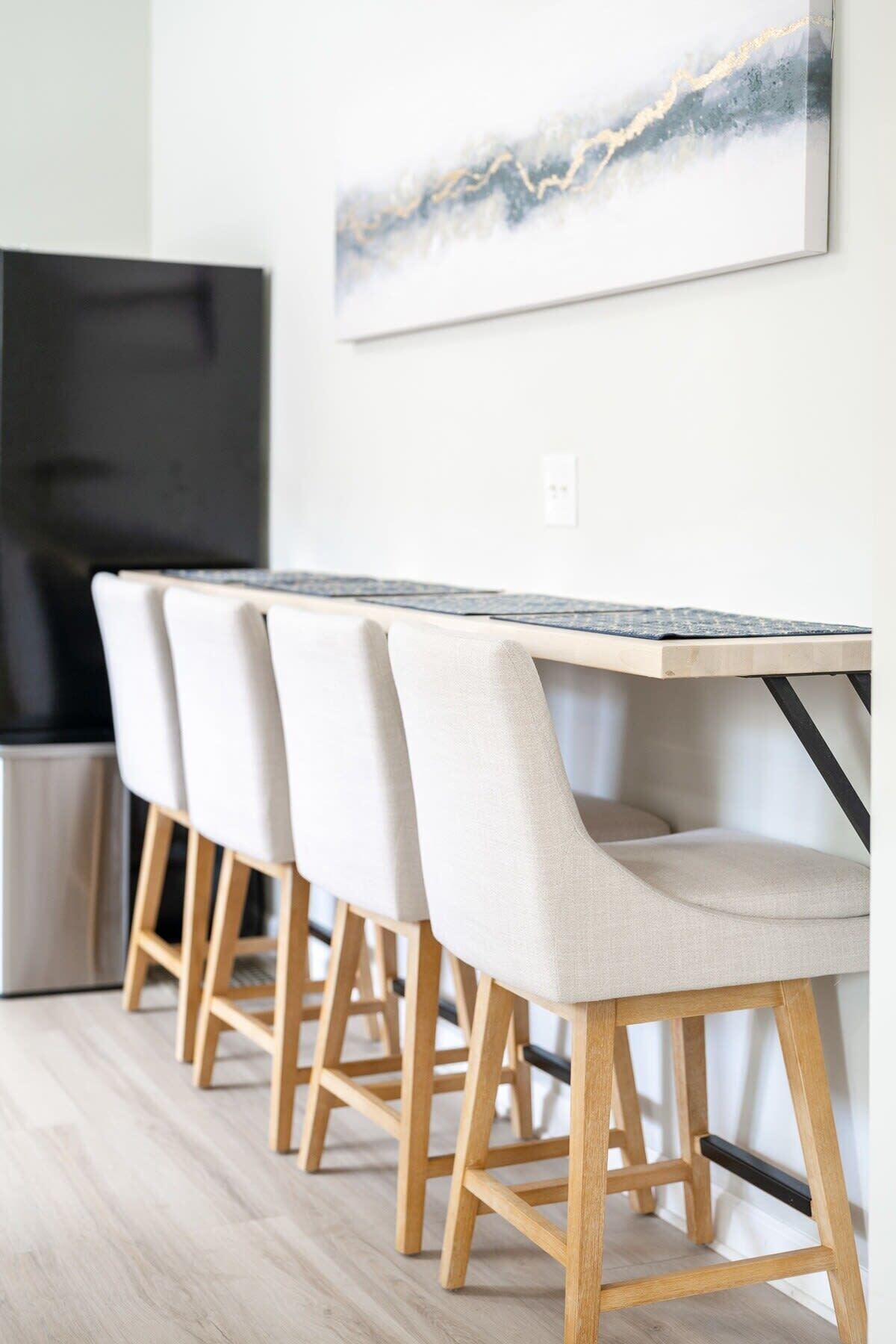 A modern dining area with a long wooden table and four upholstered chairs.