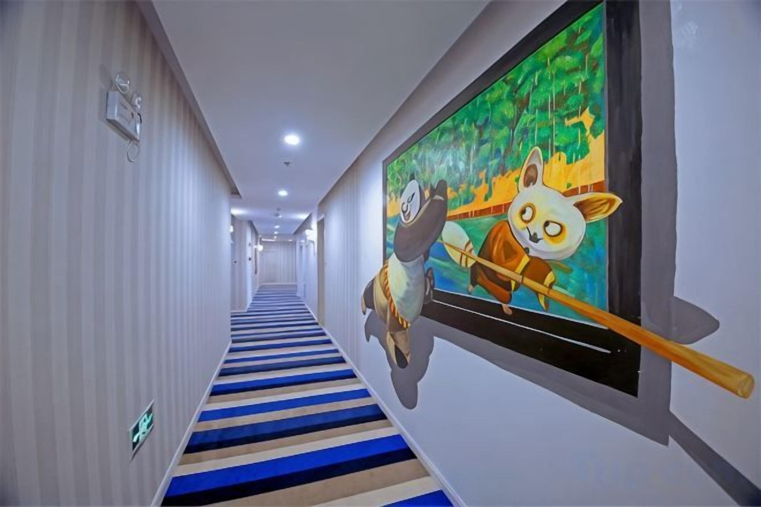 A hallway with a striped carpet, a wall-mounted painting of a panda, and a ceiling light fixture.