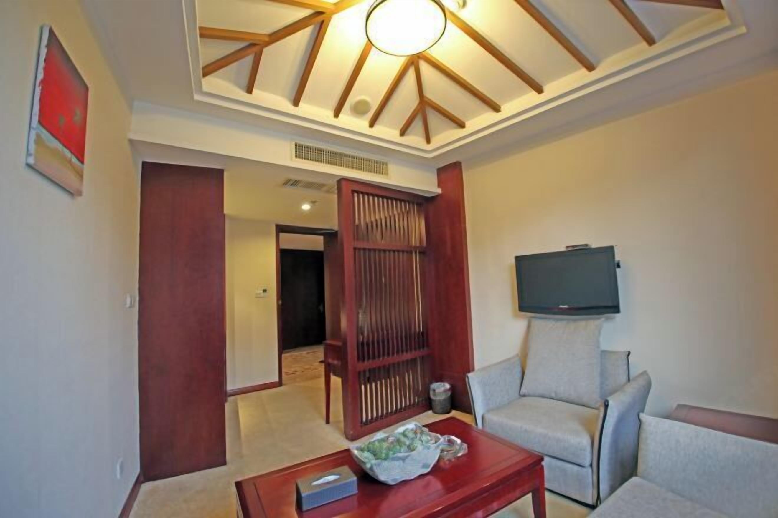 Un salon moderne doté d’un ventilateur de plafond, d’un téléviseur à écran plat fixé au mur et d’une cloison en bois.