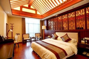 A hotel room with a large bed, a desk, chairs, a desk lamp, a telephone, and a decorative wall panel. - Qinshuiwan Holiday Hotel (Ninghai Wujia Manor) (Ninghai)