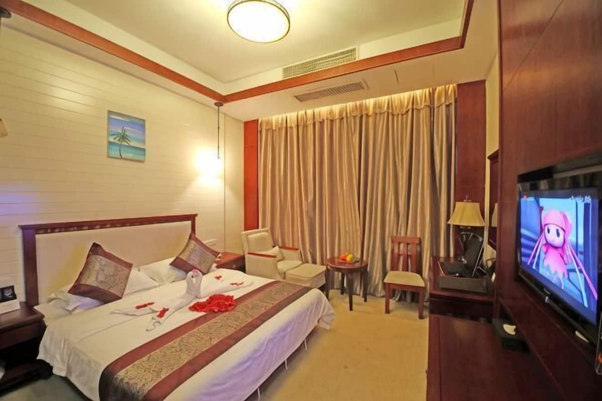 A hotel room with a bed, a TV, a desk, and a chair.