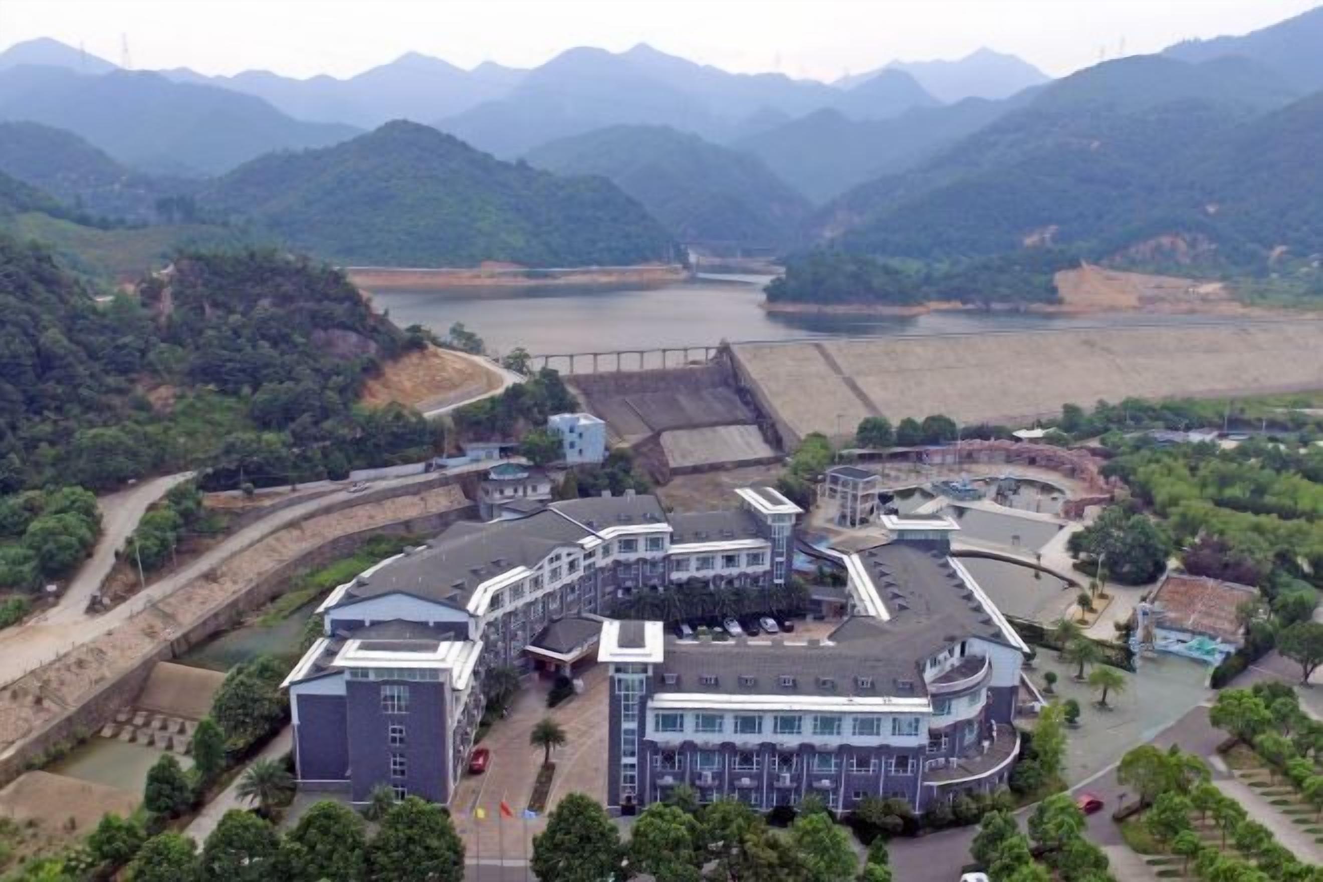 A large building complex with multiple buildings, a parking area, and a river in the background.
