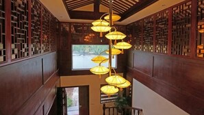 A traditional interior with wooden paneling, a staircase, and hanging lamps. - Qinshuiwan Holiday Hotel (Ninghai Wujia Manor) (Ninghai)