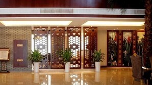 A lobby with a polished floor, a reception desk, potted plants, and a decorative wooden partition. - Qinshuiwan Holiday Hotel (Ninghai Wujia Manor) (Ninghai)