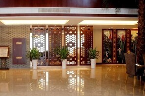 A lobby with a polished floor, a reception desk, potted plants, and a decorative wooden partition. - Qinshuiwan Holiday Hotel (Ninghai Wujia Manor) (Ninghai)