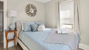Una camera da letto con un letto, un comodino, una lampada e un elemento decorativo a parete.