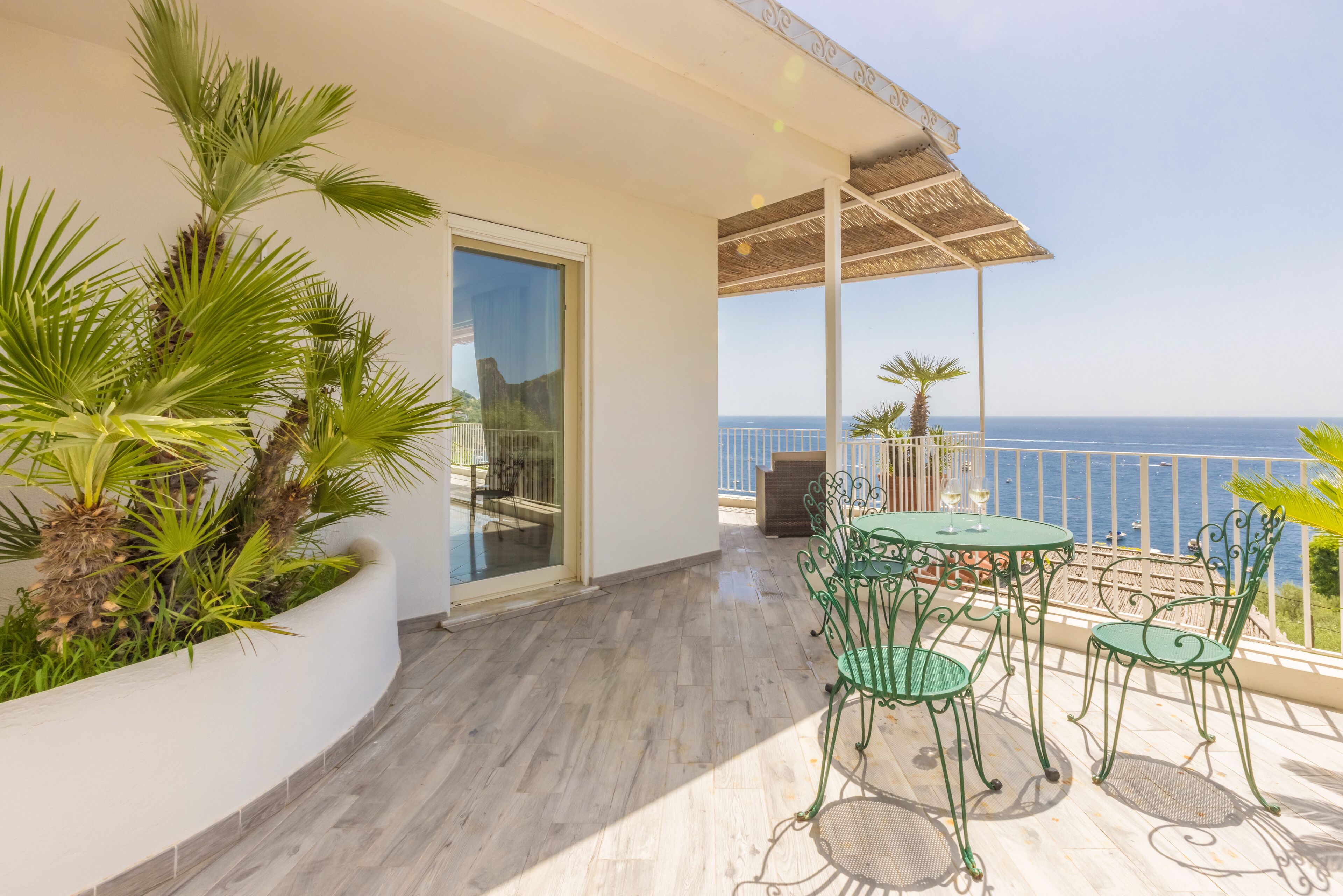 Ein Balkon mit Meerblick, einem Tisch mit Stühlen und Topfpflanzen.