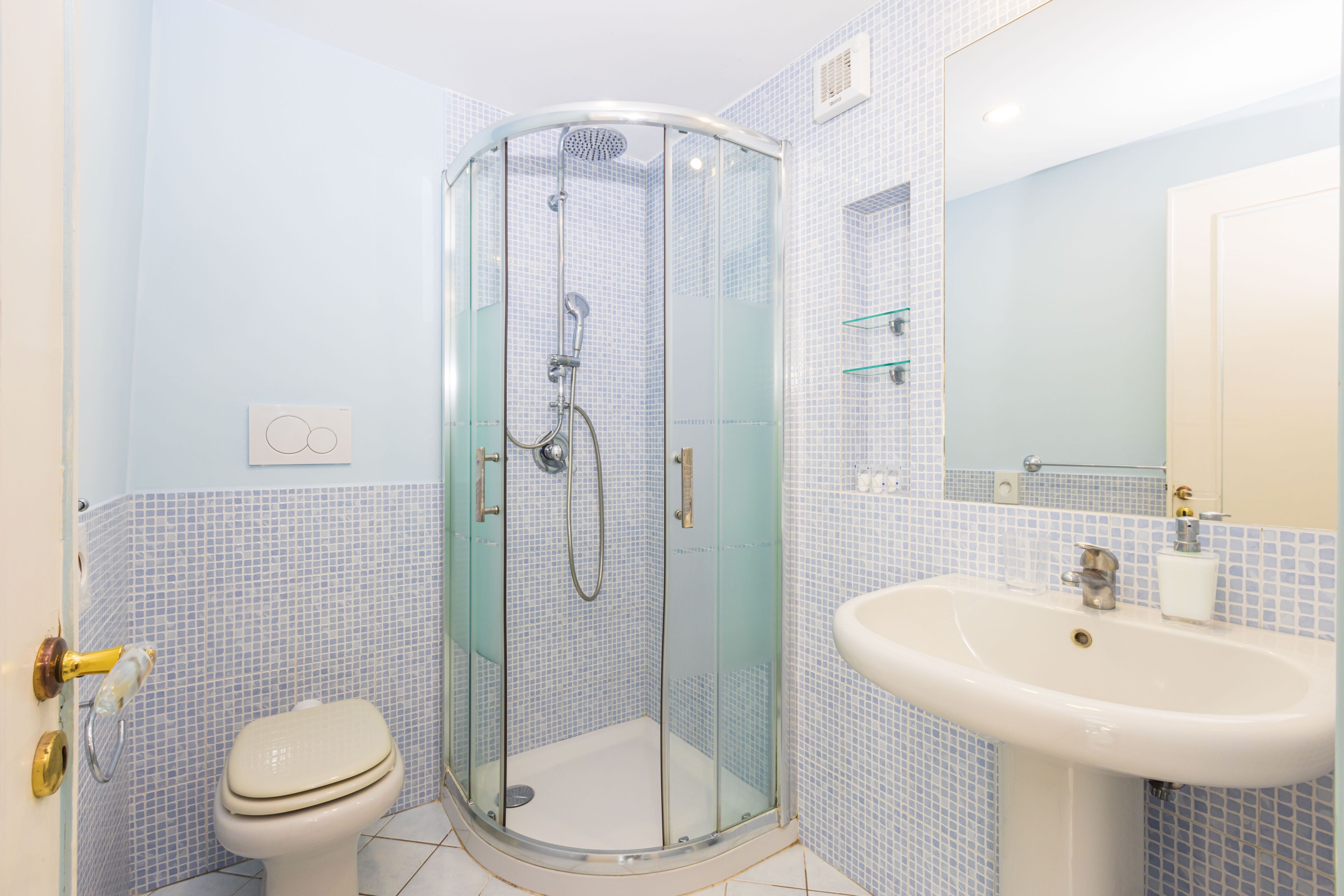 Une salle de bain avec une douche à parois de verre, des toilettes et un lavabo.