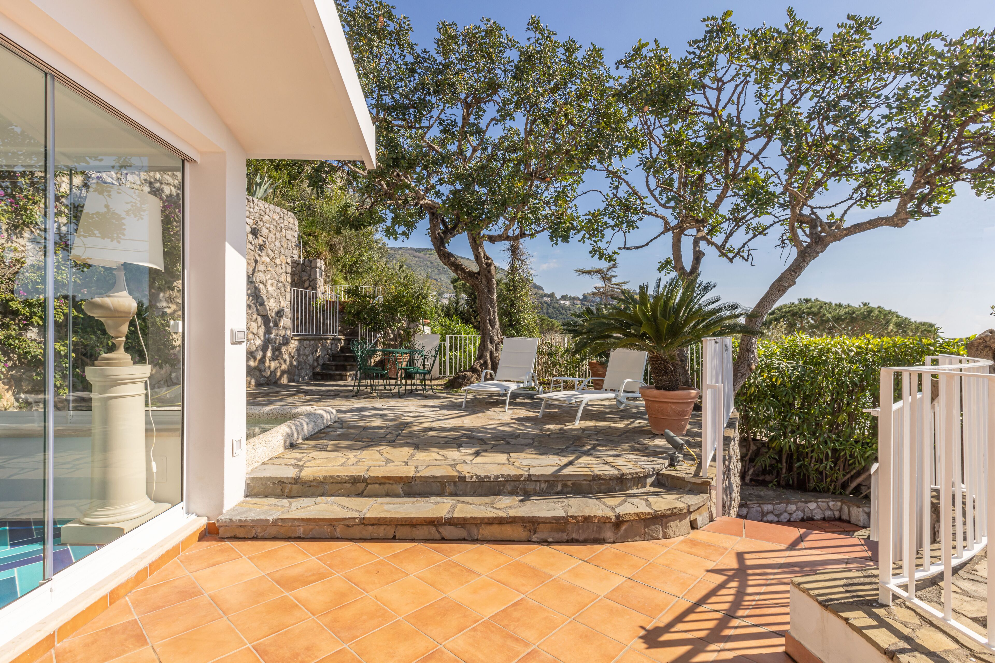 Un patio con suelo de piedra, mobiliario exterior y vistas del paisaje circundante.
