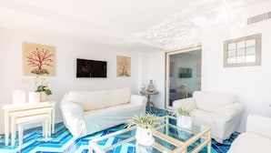 Un salon moderne avec un canapé blanc, une table basse en verre et un sol à motifs bleus.