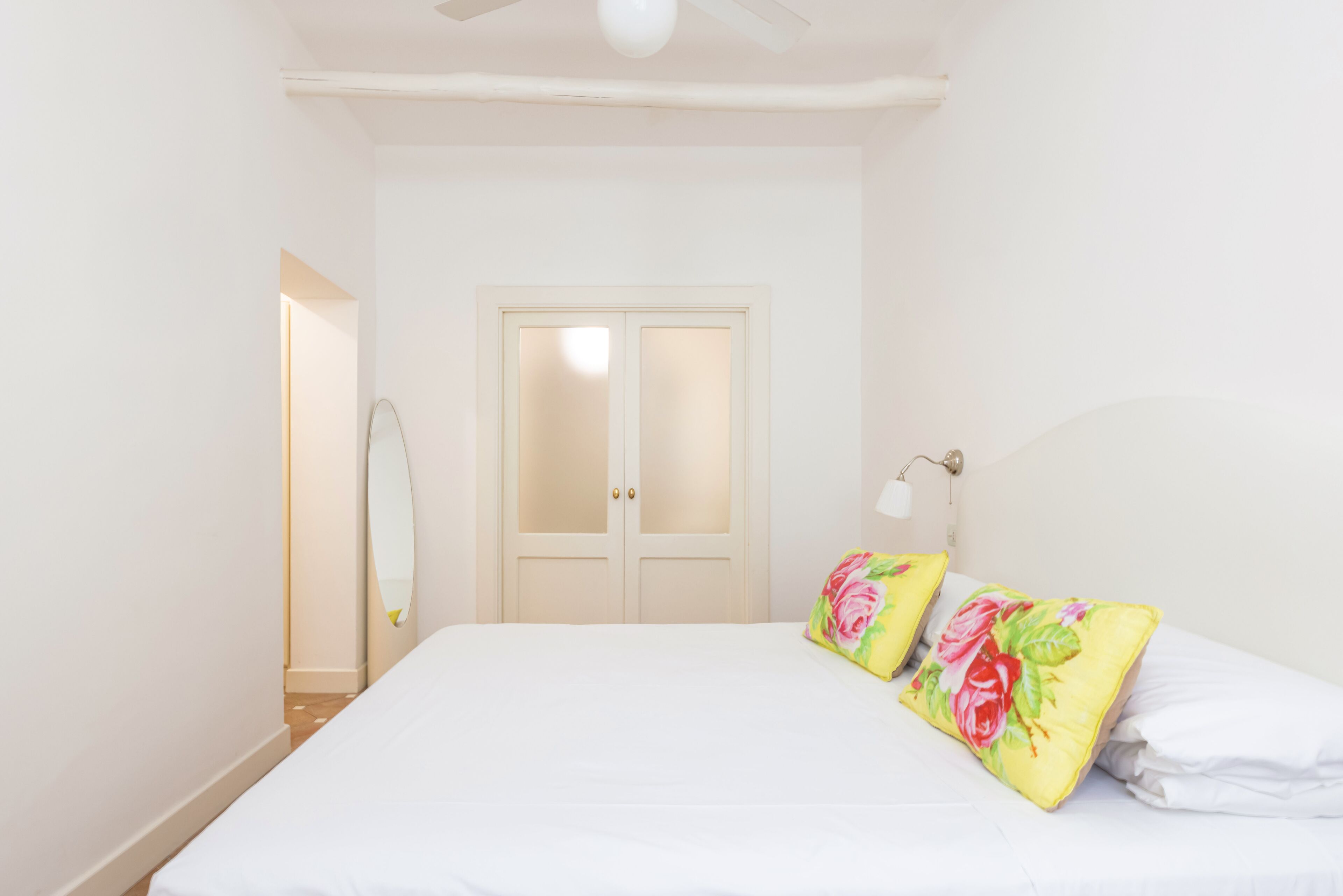 Une chambre à coucher avec un lit, un ventilateur de plafond, une porte et une lampe fixée au mur.
