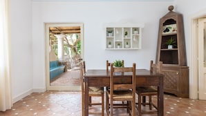 Un coin repas avec une table et des chaises en bois, une étagère blanche agrémentée de plantes et un meuble en bois surmonté d’un élément décoratif.