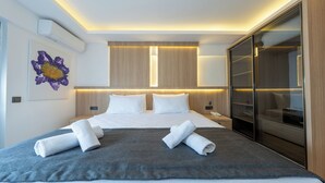 A modern hotel room with a large bed, a walk-in closet, and a wall-mounted air conditioning unit. - Skykhan Otel (Fethiye)