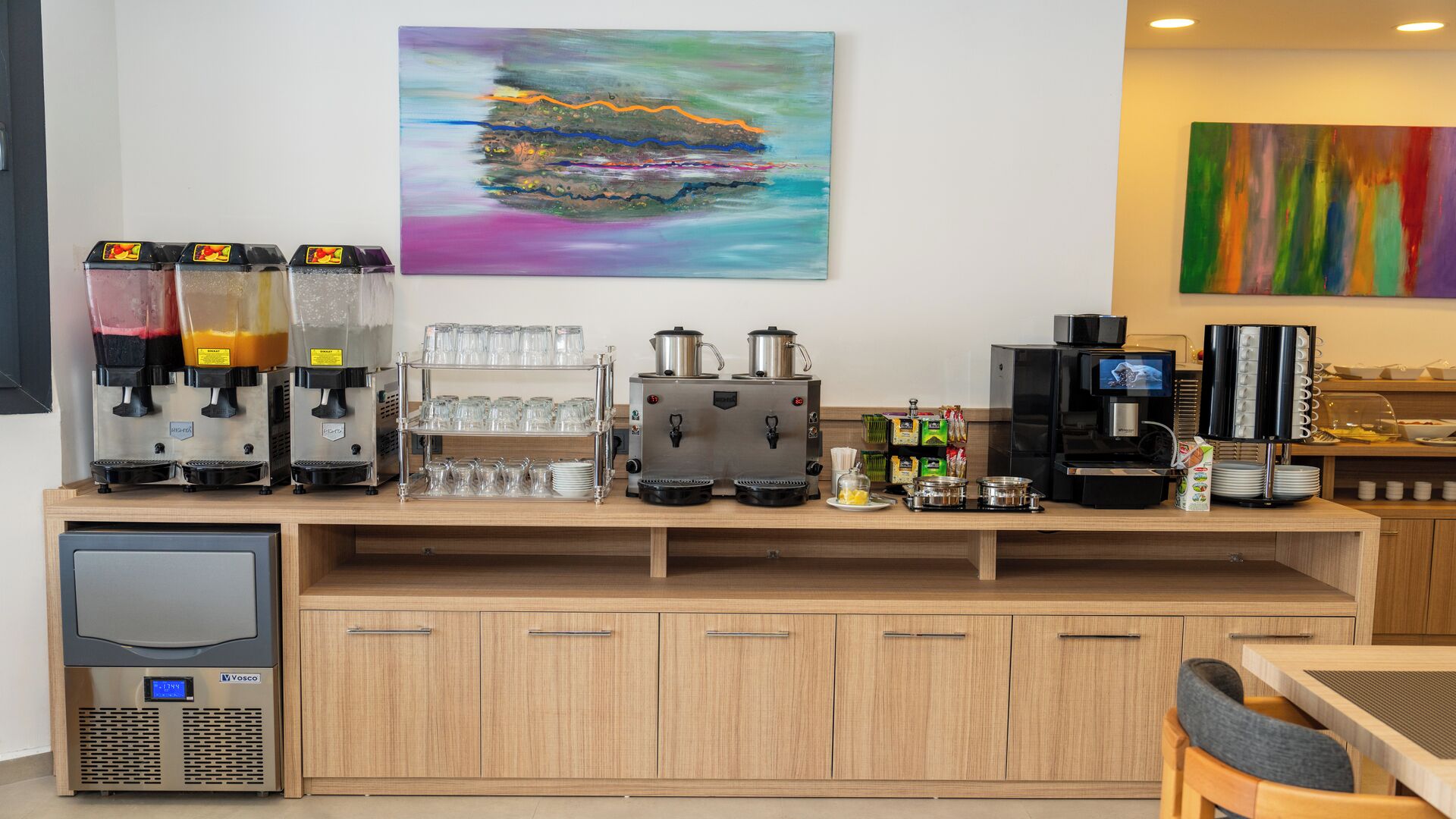 A coffee station with multiple coffee machines, a TV, and a variety of food and drink containers.