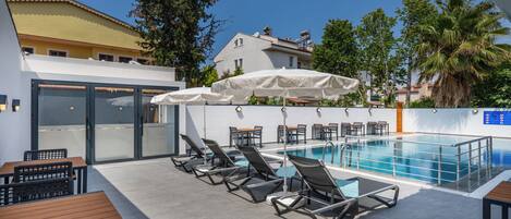 A poolside area with lounge chairs, umbrellas, and a pool.
