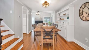 A modern kitchen with wooden flooring, white cabinetry, and a large wall clock. - Niantic Cove Waterfront Escape: Relax & Unwind (Niantic)