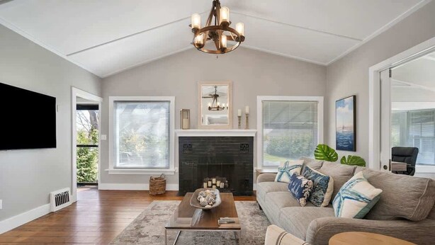 A living room with a fireplace, a sofa, a coffee table, and a chandelier. - Niantic Cove Waterfront Escape: Relax & Unwind (Niantic)