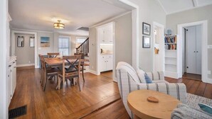 A spacious living area with a dining table, a sofa, and a bookshelf. - Niantic Cove Waterfront Escape: Relax & Unwind (Niantic)