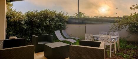 An outdoor patio with wicker furniture, a table, and chairs.