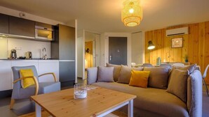 Un salon moderne avec un canapé, une table basse et un coin cuisine à l’arrière-plan.