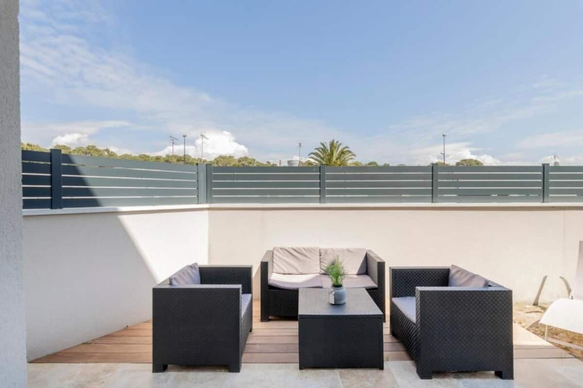 Un espace extérieur aménagé en terrasse, avec des meubles en osier, une petite table et une plante en pot.