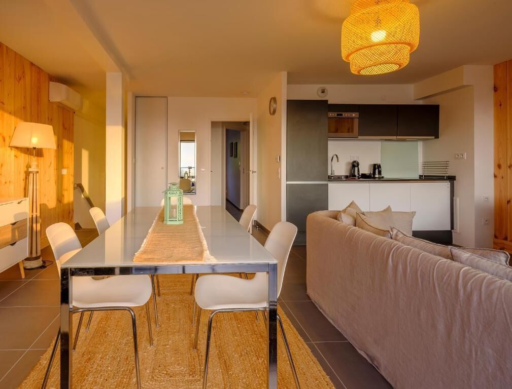 Una sala de estar moderna con una mesa de comedor, sofá y zona de cocina.