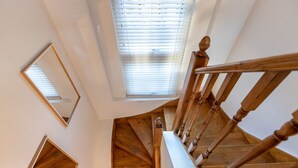 Una scala in legno con corrimano e vista del soffitto.