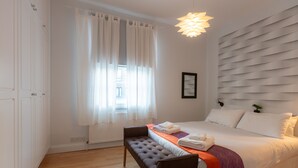 Una camera d'albergo con un letto, una panca e una finestra con tende.