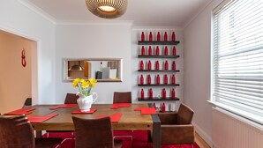 Una sala da pranzo con un tavolo in legno, sedie rosse, un vaso di fiori gialli e tovaglioli rossi.