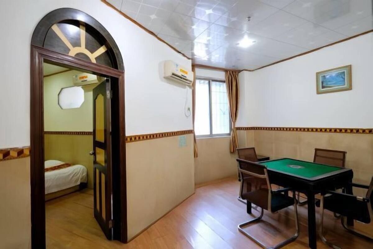 Una habitación con mesa de billar, sillas, cama, ventana con cortinas y equipo de aire acondicionado.