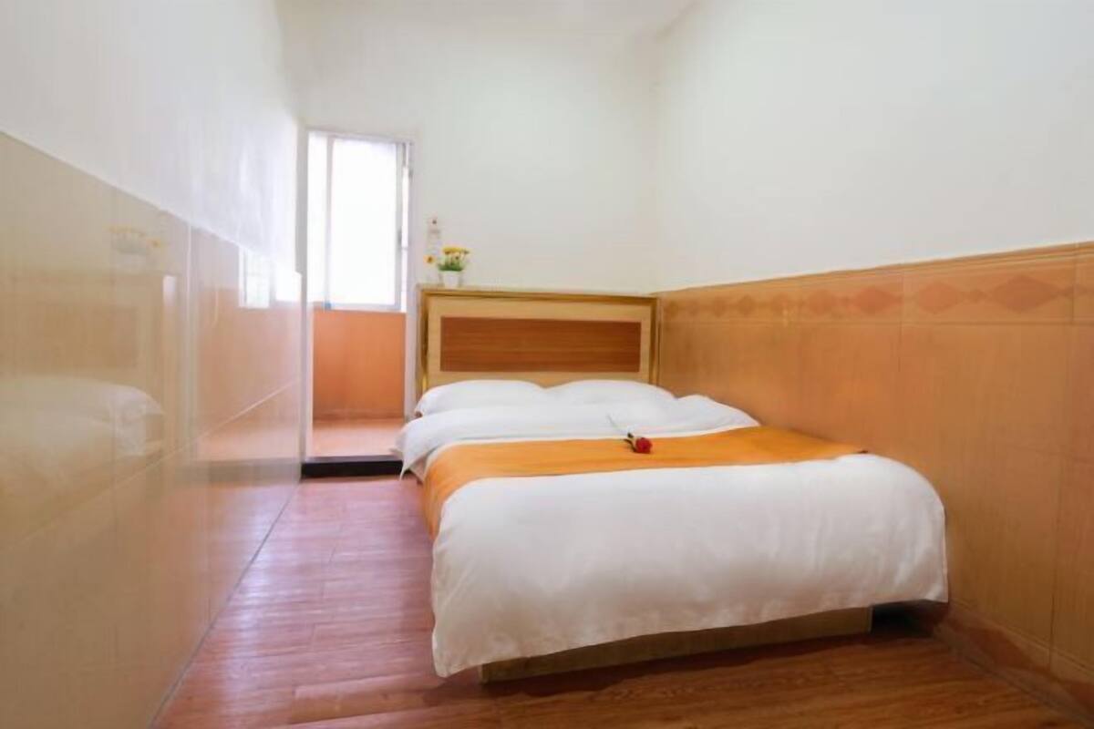 Una habitación de hotel con piso de madera, una cama con ropa blanca y un cabecero de madera.