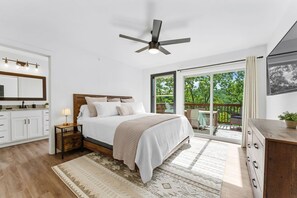 A bedroom with a bed, bedside table, lamp, and a view of the outdoors through a sliding glass door.